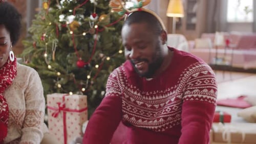Homem negro feliz recebendo presente de Natal de esposa e filha