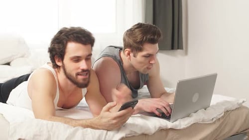 Cute Male Gay Couple Spend Time at Home. They Are Sitting Down on a Sofa and Use the Laptop.