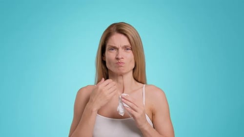 Mujer enferma de mediana edad que se siente mal y sufre de secreción nasal soplando en papel Número azul