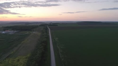 Aerial view of evening highway at sunset near the village and fields
