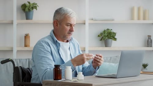 Hombre maduro enfermo y discapacitado que mide la temperatura y tiene fiebre en casa