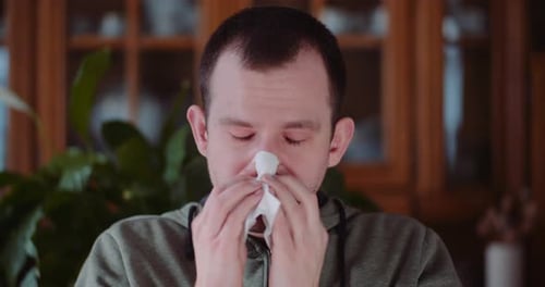 Joven débil estornudando teniendo temperatura. Tos.