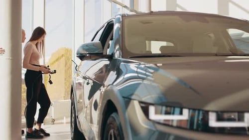 Two Happy Young Beautiful Women are Charging an Electric Car for the First Time