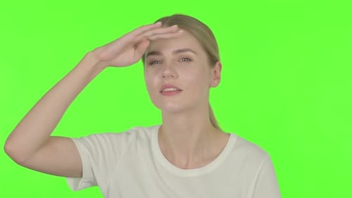 Mujer joven mirando a su alrededor, buscando la pantalla verde