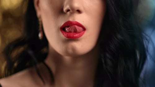Femme brune sexy et ludique en gros plan se léchant la bouche, lèvres rouges par langue
