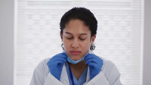 Portrait of mixed race female doctor putting a face mask on