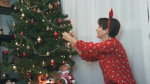 Happy charming woman is hanging ball on a Christmas tree, decorating Christmas tree, New year