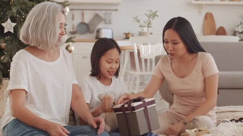 Feliz família asiática compartilhando presentes de Natal em casa