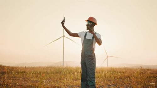 Positive Engineer in Uniform and Helmet Using Modern Smartphone for Video Call