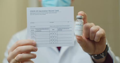 Doctor Is Holding a Vaccination Record Card and Corona Virus Vaccine Vials