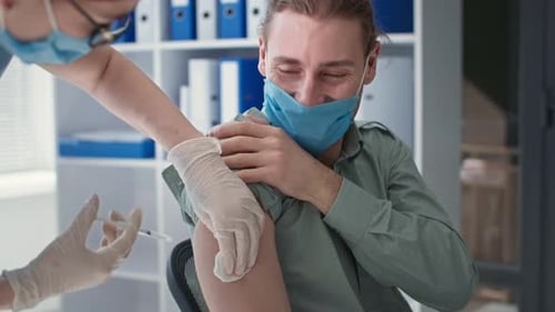 Paciente masculino feliz durante la vacunación contra el coronavirus en el consultorio médico del hospital