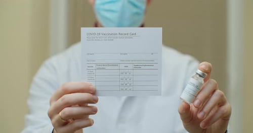 Doctor Is Holding a Vaccination Record Card and Corona Virus Vaccine Vials
