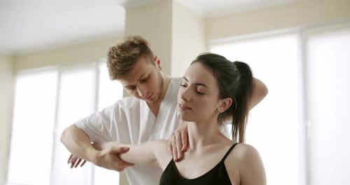 Physiotherapist Treating Wrist Shoulder and Back of Patient Examined in Hospital