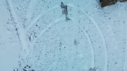 Flying over a snowy field. Straw bales are stacked. Traces of agricultural tillage under the snow.