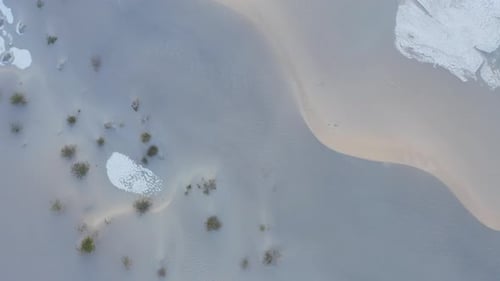 Drone slowly ascends to reveal sand dunes in the Death Valley. Top down view