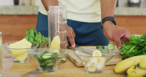 Fit african american man cooking, preparing healthy green smoothie