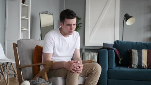 Homem com dor no joelho sentado no sofá