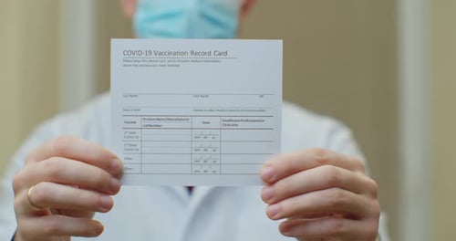 Doctor Is Holding a Vaccination Record Card and Corona Virus Vaccine Vials