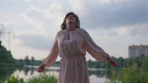 Feliz persona transgénero caucásica relajada de pie al aire libre con las manos estiradas y los ojos cerrados