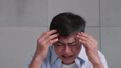 Viejo asiático con migraña.