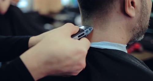 Hairdresser Professionally Does the Edging of the Hair to the Man Behind the Neck
