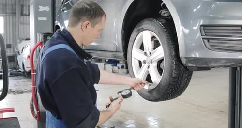 Close Shot Of Mechanic Inflating A Tire With Compressor