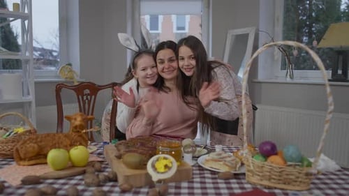 Confident Happy Mother and Daughters Waving Looking at Camera Smiling and Hugging at Home on Easter