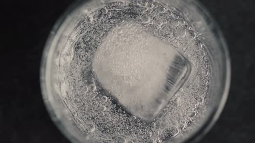 Closeup Ice Cube Glass with Sparkling Water in Slow Motion
