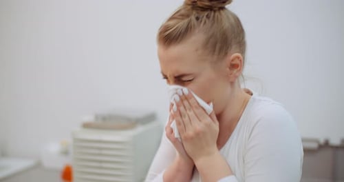 Una mujer que estornuda tiene síntomas de coronavirus