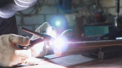 Male Mechanic in Protective Mask Doing Welds Work Using Professional Equipment