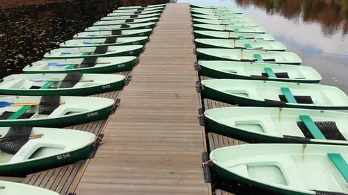 Boats Moored Along Wooden Pier on River in Autumn Park