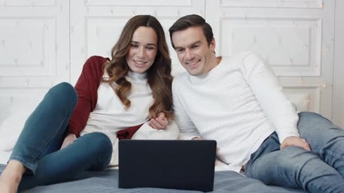 Happy Couple Watching Movie on Computer at Home Together