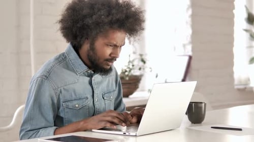 Perda frustrado homem africano criativo trabalhando no laptop